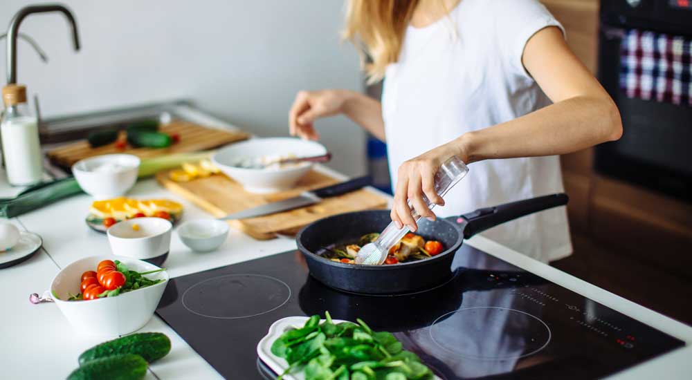 woman cooking over stove with vegetables and fruits