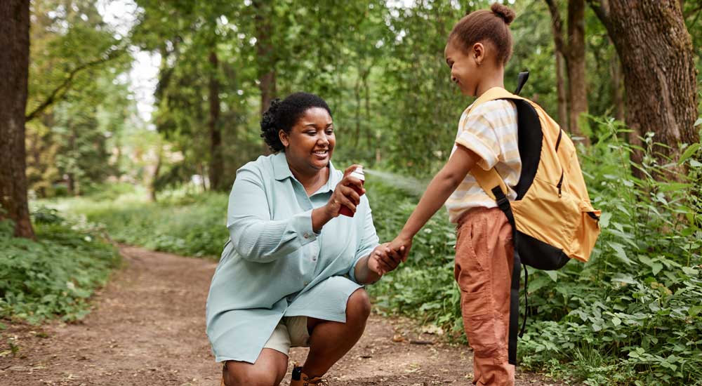 woman with bug spray outside with child