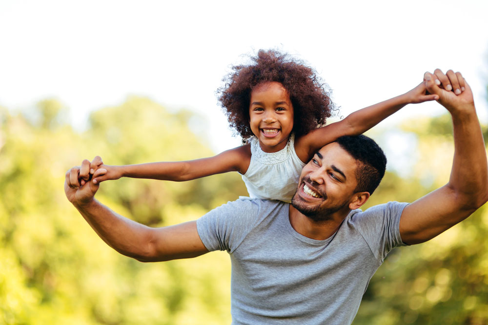 man holds hands of little girl on his back