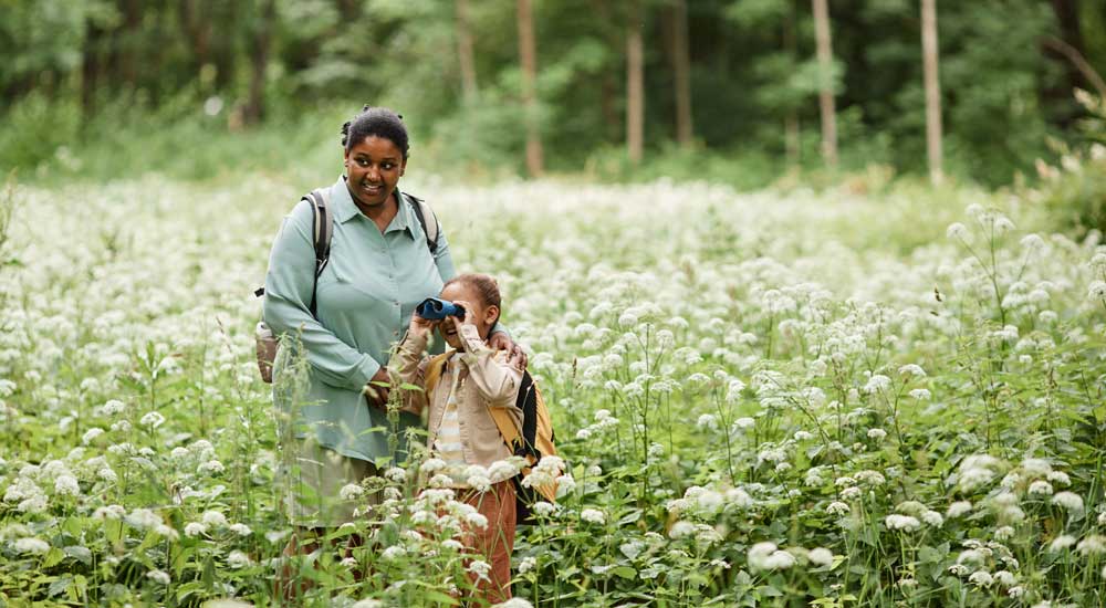 woman and girl in meadow with binoculars