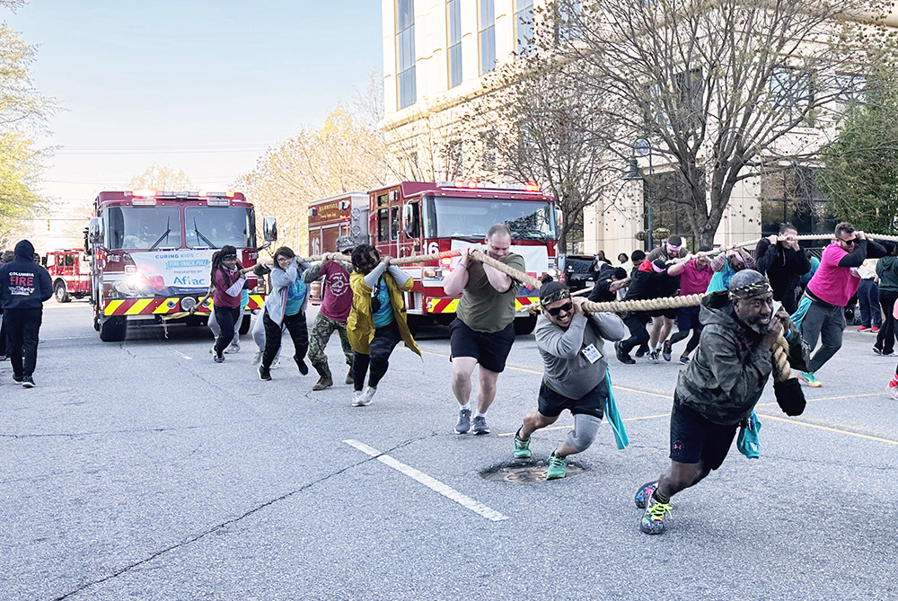 Blue Cross employees pulling a fire truck at a charity event